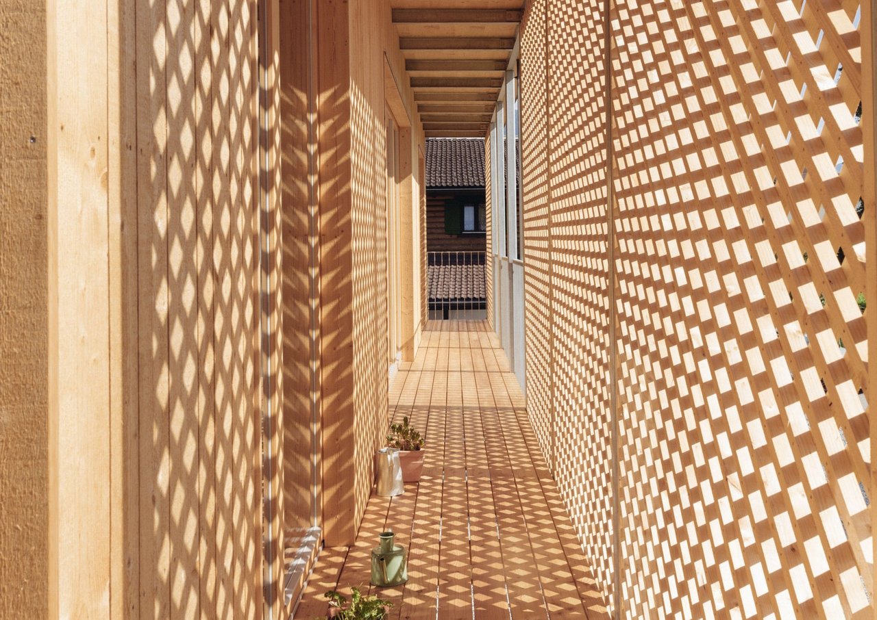 Holzgang mit offener Holzfassade und Lichtspiel